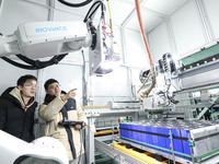 Workers are observing operations at an automated production line for PACK, an energy storage equipment manufacturing facility, in Zhangye, C...
