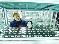 A staff member is checking accessories on an automated production line for energy storage equipment manufacturing modules in Zhangye, China,...