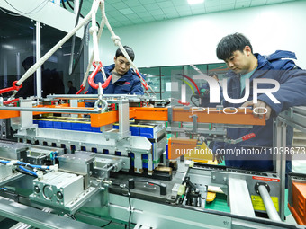 ZHANGYE, CHINA - FEBRUARY 29, 2024 - Workers are lifting modules at an automated production line for energy storage equipment manufacturing...