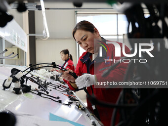 A worker is producing automotive wiring harness products at a workshop of an auto parts manufacturer in Binzhou, Shandong Province, China, o...