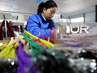 A worker is producing automotive wiring harness products at a workshop of an auto parts manufacturer in Binzhou, Shandong Province, China, o...