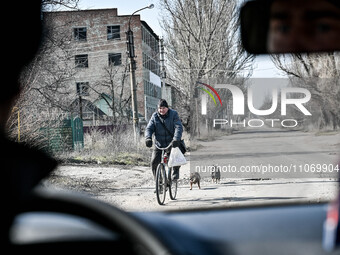 A man is riding a bicycle down the street in Huliaipole, Zaporizhzhia Region, Ukraine, on March 7, 2024. NO USE RUSSIA. NO USE BELARUS. (