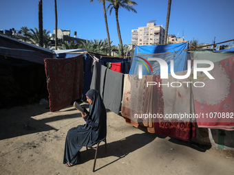 A Palestinian woman is reading the Koran near a camp for displaced people on the second day of the Muslim holy fasting month of Ramadan in D...