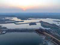 Construction workers and large machinery are working on the Heilongtan Reservoir reinforcement project in Lianyungang, China, on March 12, 2...