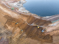 Construction workers and large machinery are working on the Heilongtan Reservoir reinforcement project in Lianyungang, China, on March 12, 2...