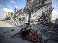 A Palestinian boy is sitting amidst the rubble and inspecting the damages in Qatari-funded Hamad City, following an Israeli raid, amid the o...