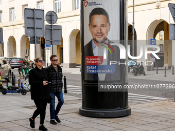 People walk in front of a local government election poster that presents Raafal Trzaskowski, a candidate for a president of Warsaw in the ce...