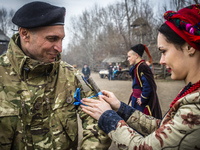 Woman dressed in traditional costume ties a branch on the hand of Georgia National Legion soldier (one of the most important rite of Ukraini...