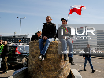 Polish farmers hold Polish flags and sit on hay during a protest on Mogilskie roundabout in the centre of Krakow, the capital of the Lesser...