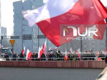 Polish farmers and their supporters stand with Polish flags during a protest on Mogilskie roundabout in the centre of Krakow, the capital of...