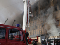 A firefighter is working on a lifting platform to address the aftermath of a rocket attack by Russian troops on a private enterprise in Khar...