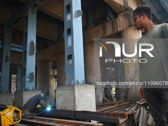 A worker is welding iron rods at the repair site of a bridge in Kolkata, India, on March 24, 2024. (