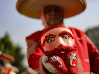 A person dressed in a traditional Charro suit is showing a Chinelo mask during the Comparsa Faisanes, as part of the closing of the annual S...