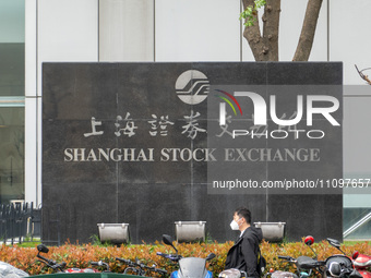 A citizen is walking past the Shanghai Stock Exchange in front of the Lujiazui Securities Building in Pudong, Shanghai, China, on March 25,...