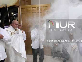 Father Bernardo Lanuza, OFM, is holding the wrapped consecrated Eucharist hosts while an altar server is smoking religious incense for the p...