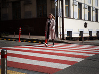 A woman is crossing a street at a zebra crossing in Kyiv, Ukraine, on March 28, 2024. (