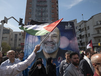 An Iranian man is waving a Palestinian flag in front of a portrait of Mohammad Reza Zahedi, a senior commander in the Iranian Revolutionary...