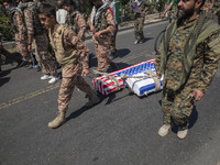 A member of the Islamic Revolutionary Guard Corps (IRGC) is carrying two coffins, symbolizing the death of Israel and the U.S., during a fun...