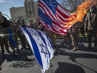 Members of the Islamic Revolutionary Guard Corps (IRGC) are burning flags of Israel and the U.S. during a funeral for members of the IRGC Qu...