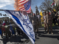 Members of the Islamic Revolutionary Guard Corps (IRGC) are burning flags of Israel and the U.S. during a funeral for members of the IRGC Qu...