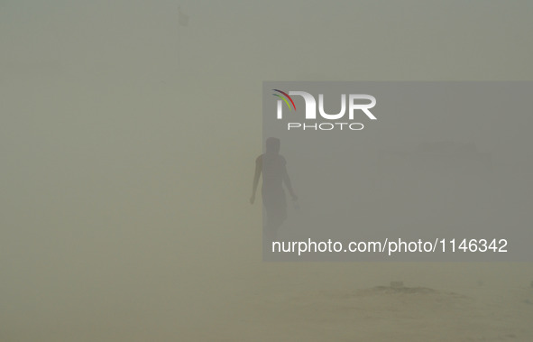 An indian commuter walks on, in a dust storm,during a hot day, in Allahabad on April 7,2016. 