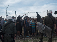 Refugees in front of a fence while police protects it in Idomeni camp, on April 7, 2016 (