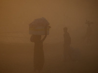 Indian people walk on the banks of holy sangam,during heavy dust storm, in Allahabad on April 10,2016. (