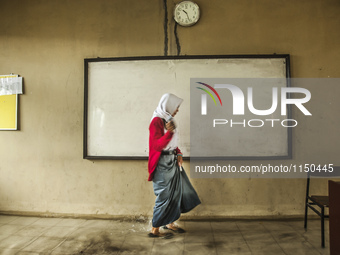 A student walking in flooded classroom in high school SMKN 1, Village Kramat Sari, Pekalongan, Central Java, Indonesia, on April 11, 2016. T...