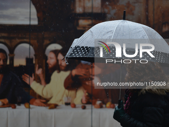 A woman passes in front of Dublin's Last Supper photographic work during an April shower.
Dublin, Ireland. On Monday, 11 April 2016. (