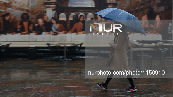 A woman passes in front of Dublin's Last Supper photographic work during an April shower.
Dublin, Ireland. On Monday, 11 April 2016. 