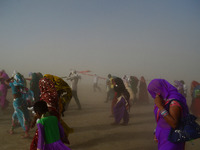  Indian hindu devotees cover their faces to protect themselves from dust storm and heat waves as they return after taking a holy dip at holy...