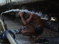 An indian passenger takes a quick bath to beat the heat,at Allahabad railway station, during a hot day, in Allahabad on April 13,2016. (