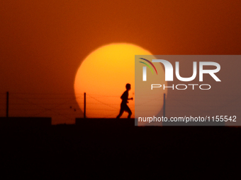 An indian sprinter runs on the fringes of a road, during sunset, in Allahabad on April 14,2016. (