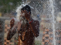 An indian sadhu (holy man) takes a shower inside a munucipal water line, to beat the heat , during a hot day in Allahabad on April 16,2016.A...