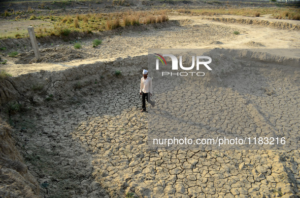 An indian farmer walks on a dried and cracked surface of his farml, in shringerpur village, 17 kms from Allahabad, during a hot day on April...