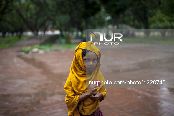 A homeless child walking in a park cover her head with a yellow cloth to save from rain water in Dhaka, Bangladesh on May 24, 2016. 