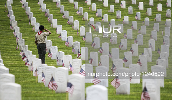 A boy scout salutes after placing U.S. flag in front of a grave stone at the Los Angeles National Cemetery, for the Memorial Day in Los Ange...