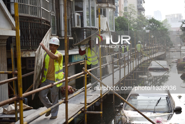 Workers set up a temporary trestle at a neighborhood in Wuhan, capital of central China's Hubei Province, July 12, 2016. In order to prepare...