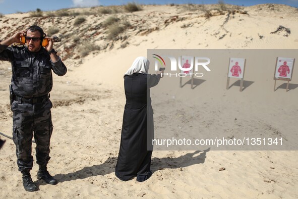 A Palestinian girl aims a pistol as she prepares to fire at a target during a training session for the families of Hamas officials, organize...