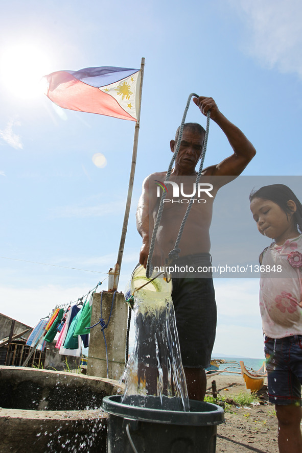 Tacloban, Philippines - Rigador Magbua, 52 fetches water for her granddaughter in Tacloban City on June 11, 2014. June 12 marks the Philippi...