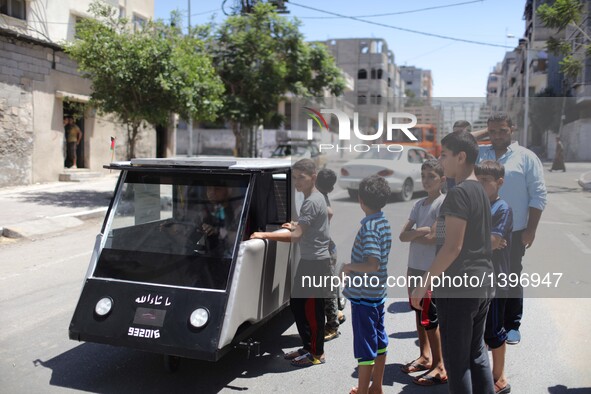 Palestinian children watch the solar car made by Palestinian students Jamal Mikaty and Khaled Bardawil in Gaza City, on Aug. 16, 2016. Two P...