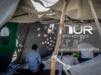 Refugees man pray at a makeshift refugee camp on the Serbian side of the border with Hungary near the town of Horgos on August 12, 2016. (