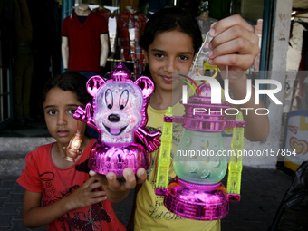 A Palestinian girls hold traditional Ramadan lanterns at a market in Rafah in the southern Gaza Strip on June 28, 2014. Starting on Sunday,...