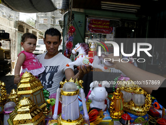 A Palestinian man carries his son and buys her lantern traditional Ramadan at a market in Rafah in the southern Gaza Strip on June 28, 2014....