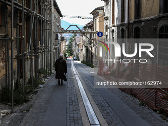 An old woman walks along the street in L'Aquila, Italy, on July 2, 2014. On the sides, damaged buildings after the quake of April 6, 2009. (