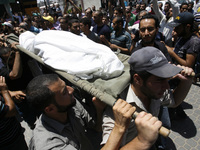 Palestinian mourners chant slogans as they carry the bodies of eight members of the Al Haj family, who were killed in an Israeli missile str...