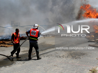 Palestinian Firefighters trying to put out the fire after Israeli tanks firing shells Karni in the east of Gaza City on, 12 July 2014. (