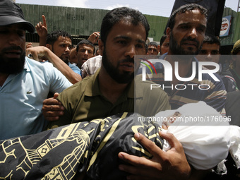 The father of three-year-old Palestinian child, Mouid al-Araj, carries his grandsons' body during his funeral in Khan Yunis, in the southern...