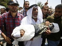 The grandfather (C) of three-year-old Palestinian child, Mouid al-Araj, carries his grandsons' body during his funeral in Khan Yunis, in the...