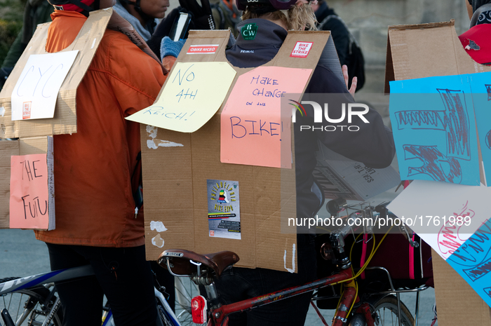Cardboard capes form the base on which several protest signs are mounted, as carried by cyclist participating in protest bike ride in Center...
